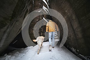 Man with dog during winter hike in rocks