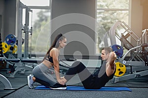 Man doing abdominal crunches press exercise with female personal trainer.