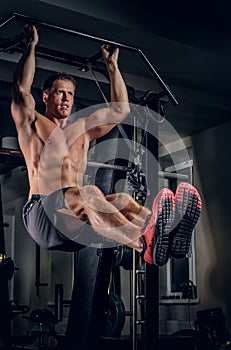 A man doing abs workouts on pull up bar.