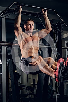 A man doing abs workouts on pull up bar.