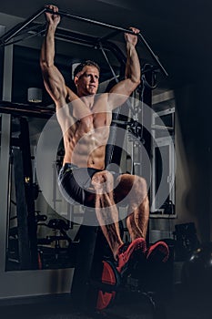 A man doing abs workouts on pull up bar.