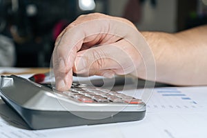 Man doing accounts with a calculator and reviewing cash and money flows, projections and invoices. Concept work at home, checking