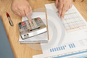 Man doing accounts with a calculator and reviewing cash and money flows, projections and invoices. Concept work at home, checking