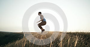 Man doing burpees exercise fitness workout outdoors. Slow motion. Jump in the air with his hands touching the knees.