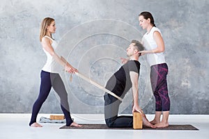 Man doing camel yoga pose in gym with his instructors