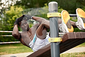 Man doing crunches. Core outdoor workout. Black athlete exercising.