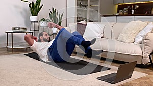 Man Doing Elbow-To-Knee Abs Crunches Exercise via Laptop Indoors