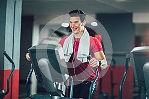 Man doing exercise on elliptical cross trainer in sport fitness gym club