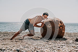 Man doing exercise outdoors near to old rusty floating marine mine on the beach with rocky shore and sea background