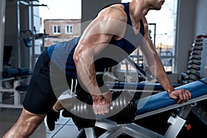 Man doing exercises with one dumbbell in the gym close-up