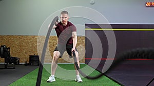 Man doing exercises with ropes during crossfit training at gym.