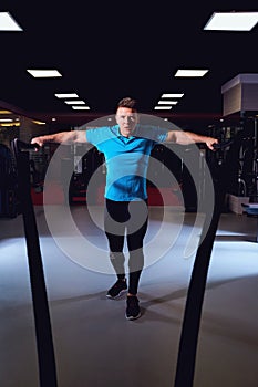 Man is doing exercises working out with a rope in the gym