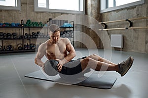 Man doing fitness workout, practicing abs exercise with med ball in gym