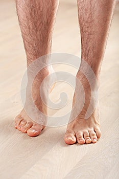 Man doing flatfoot correction gymnastic exercise standing on toes at home