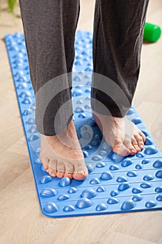 Man doing flatfoot correction gymnastic exercise walking on massage mat at home