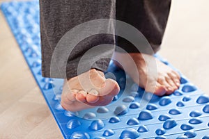 Man doing flatfoot correction gymnastic exercise walking on massage mat at home