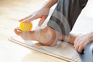 Man doing flatfoot correction self massage with a ball at home