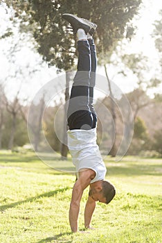 Man doing handstand on grass in the park.