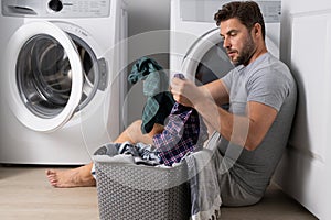 Man doing laundry at home near washing machine. Husband man doing laundry at home. Sexy guy washer putting clothes in