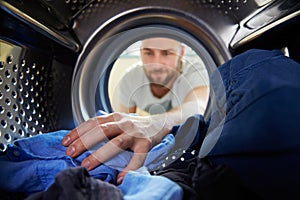 Man Doing Laundry Reaching Inside Washing Machine