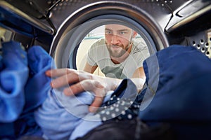 Man Doing Laundry Reaching Inside Washing Machine photo