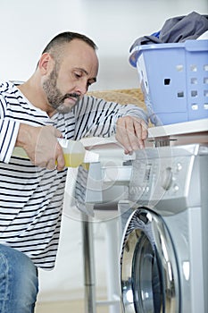 Man doing laundry reaching inside washing machine