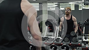 Man doing lift-ups, holding dumbbells in hands, workout for shoulder muscles