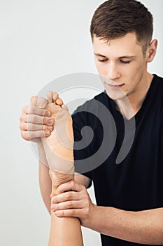 Man is doing massage foot to beautiful young woman at spa. Concept of healthy lifestyle.