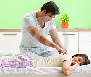 Man doing massage to his wife in bedroom