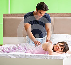 Man doing massage to his wife in bedroom