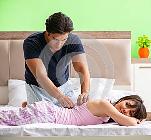 Man doing massage to his wife in bedroom