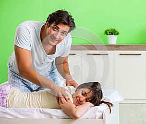 Man doing massage to his wife in bedroom