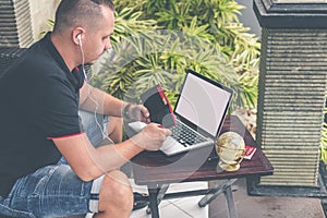 Man doing online shopping with credit card, laptop and luxury snakeskin python wallet. Man online shopping concept.