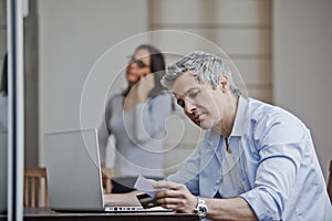 Man doing online shopping with his wife talking on a mobile phone