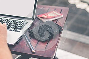 Man doing online shopping with laptop and luxury snakeskin python wallet. Man online shopping concept.