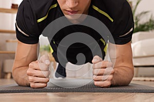 Man doing plank exercise on floor at home, closeup