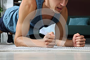 Man doing plank exercise on floor at home, closeup