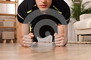 Man doing plank exercise on floor at home, closeup