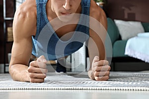 Man doing plank exercise on floor at home, closeup