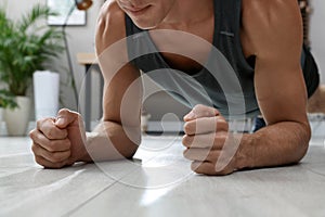 Man doing plank exercise on floor at home, closeup