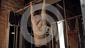 Man doing pull-up bar abdominal exercise in gym