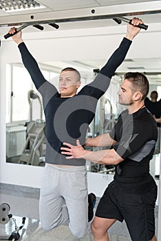 Man Doing Pull-Ups Exercises With Personal Trainer