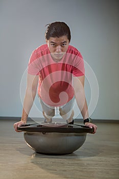 Man doing push-up on bosuball