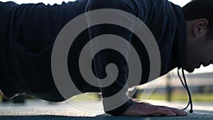 A man doing a push up in a park on cold weather. Close up view.