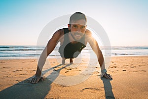 Man doing push ups or exercising on the beach during sunset. Healthy lifestyle