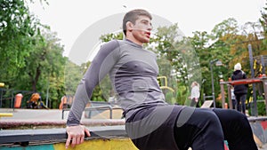 Man doing push ups on railing, under tree, in park for leisure and fun