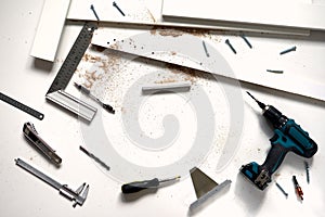 Man doing renovation work at home, drilling with a screwdriver. Group of repair tools on wooden white background