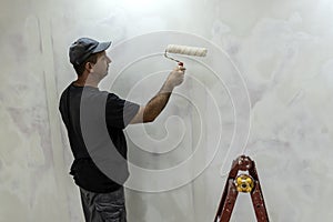 Man doing repairs, finishing room, plasterers, puttied and painted walls photo