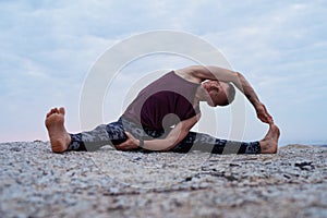 Man doing the revolved head to knee pose outdoors
