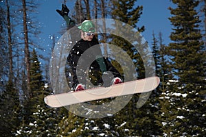 Man doing snowboarding trick jump down snowy hill in the mountains